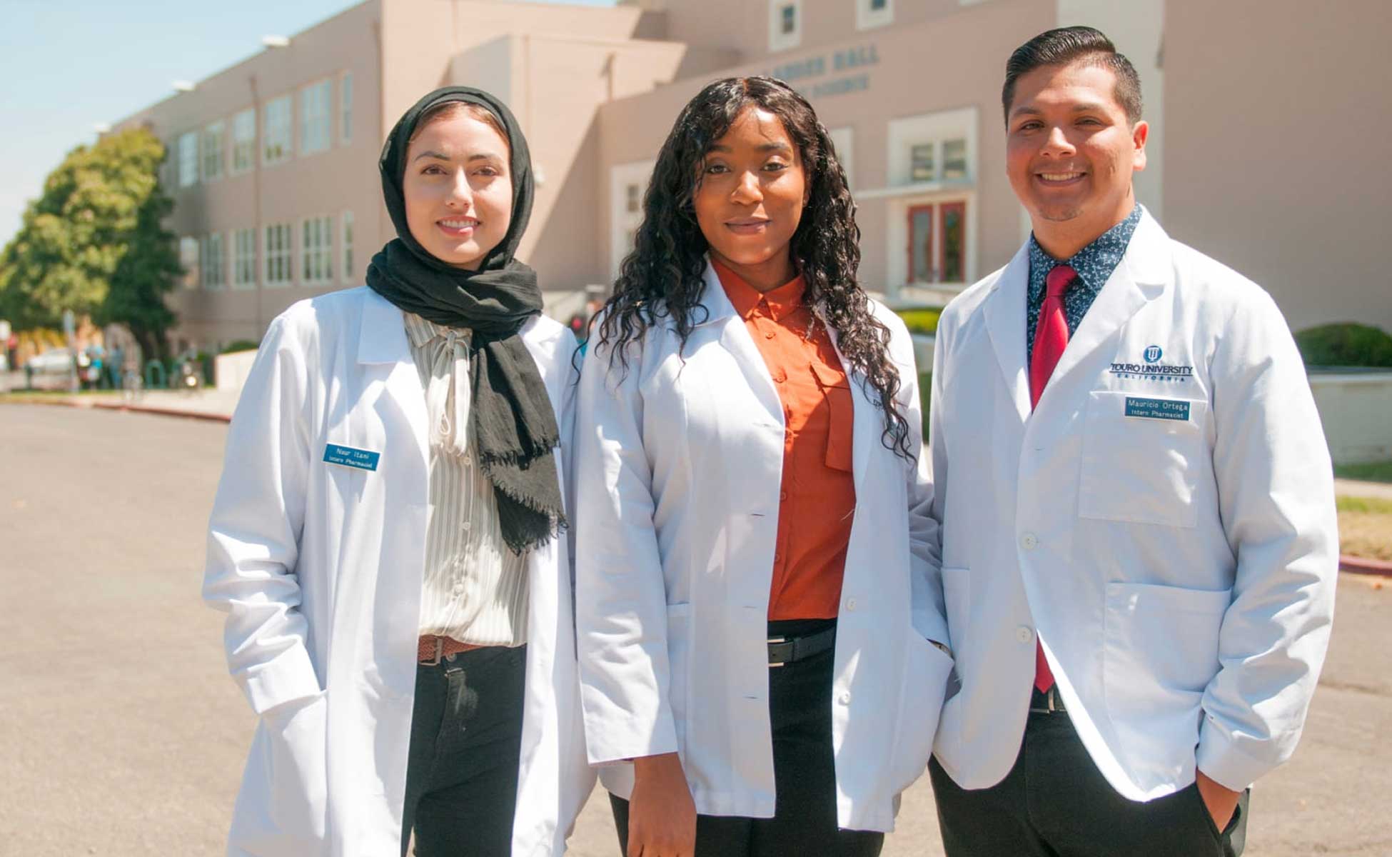 Group of TUC students smiling on campus and wearing white coats