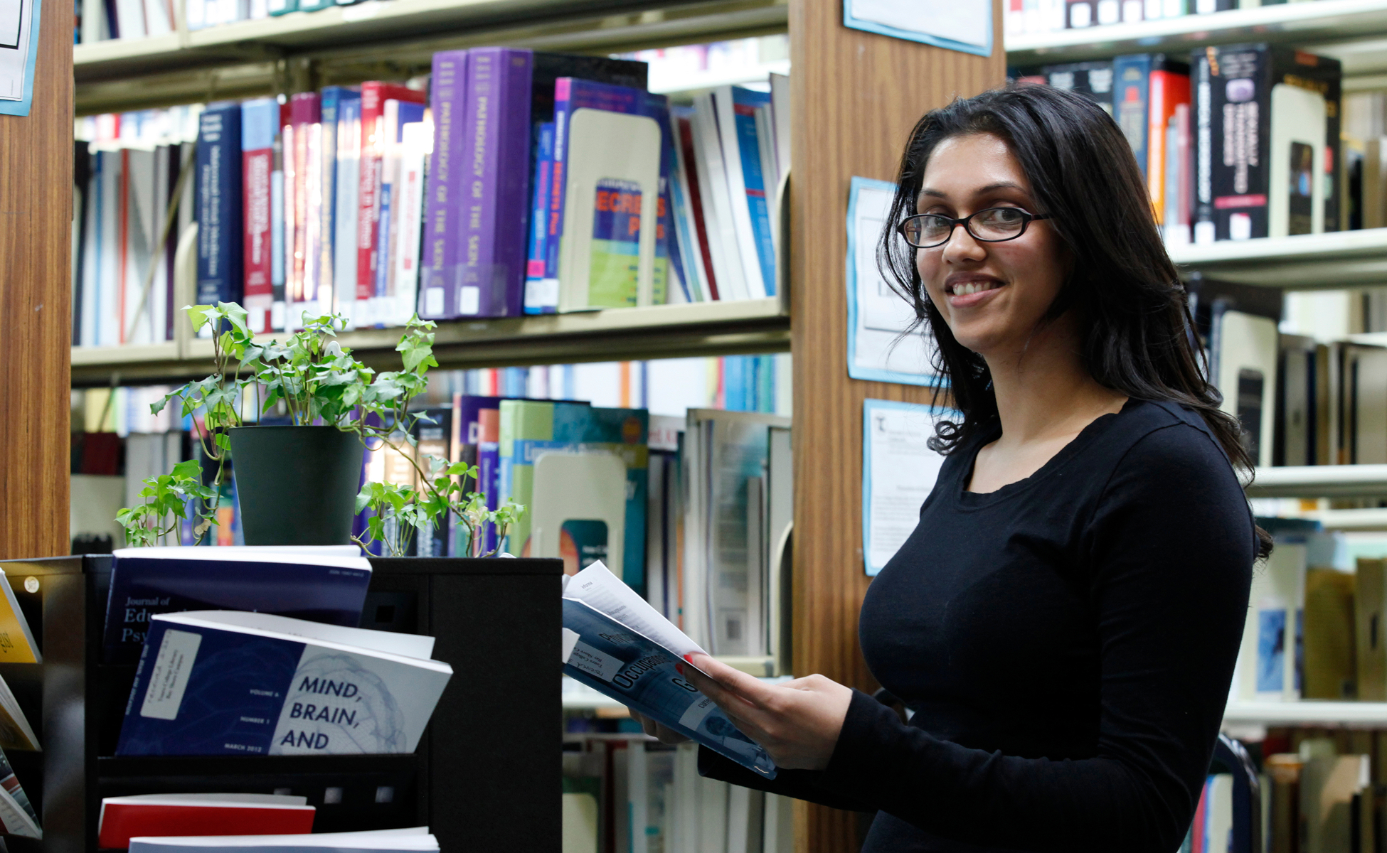 Student smiling while holding book in library