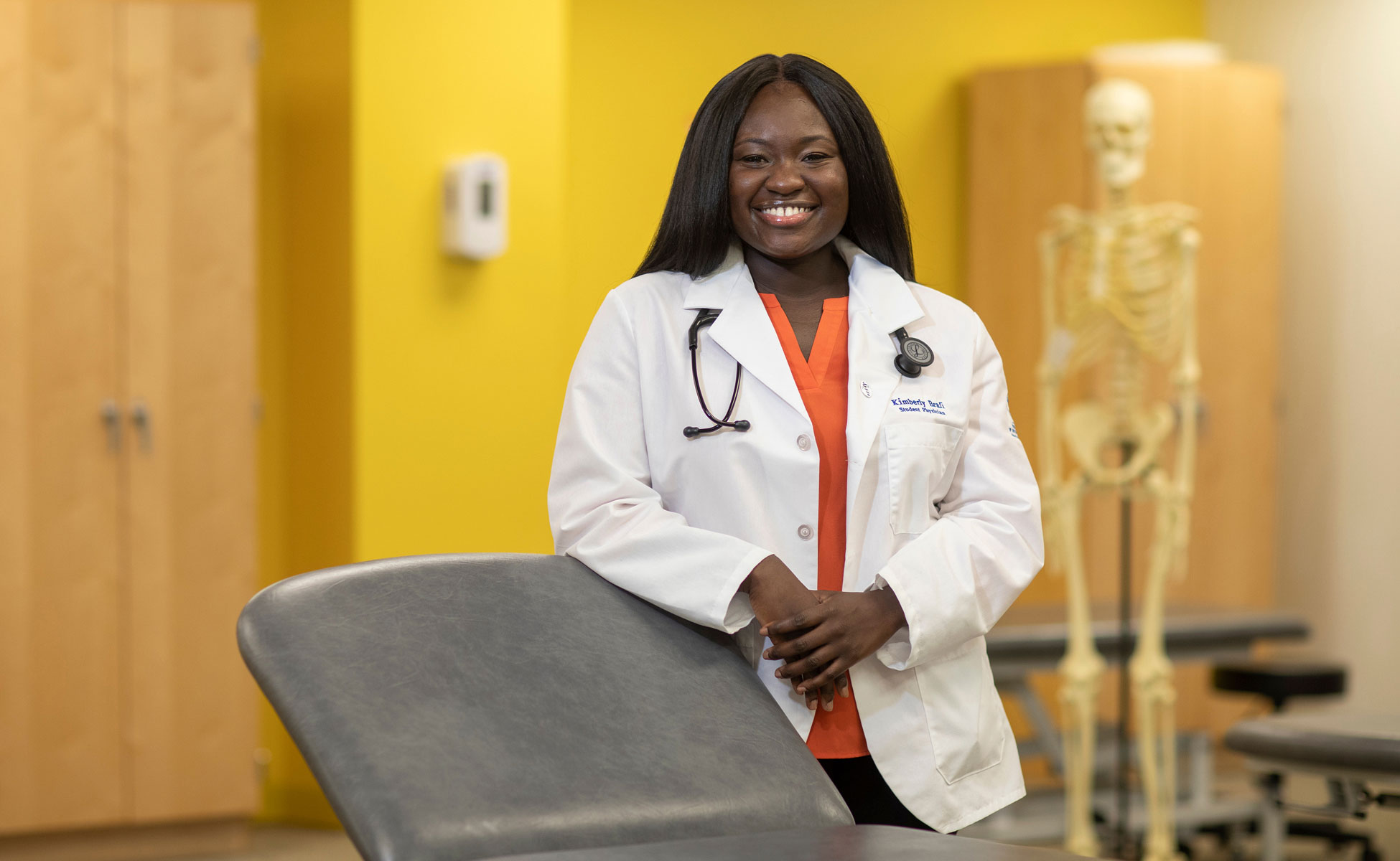 Female student smiling in clinic while wearing white coat