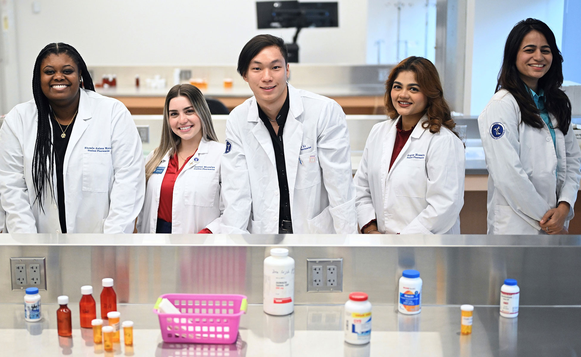 Group of students smiling at work table with equipment