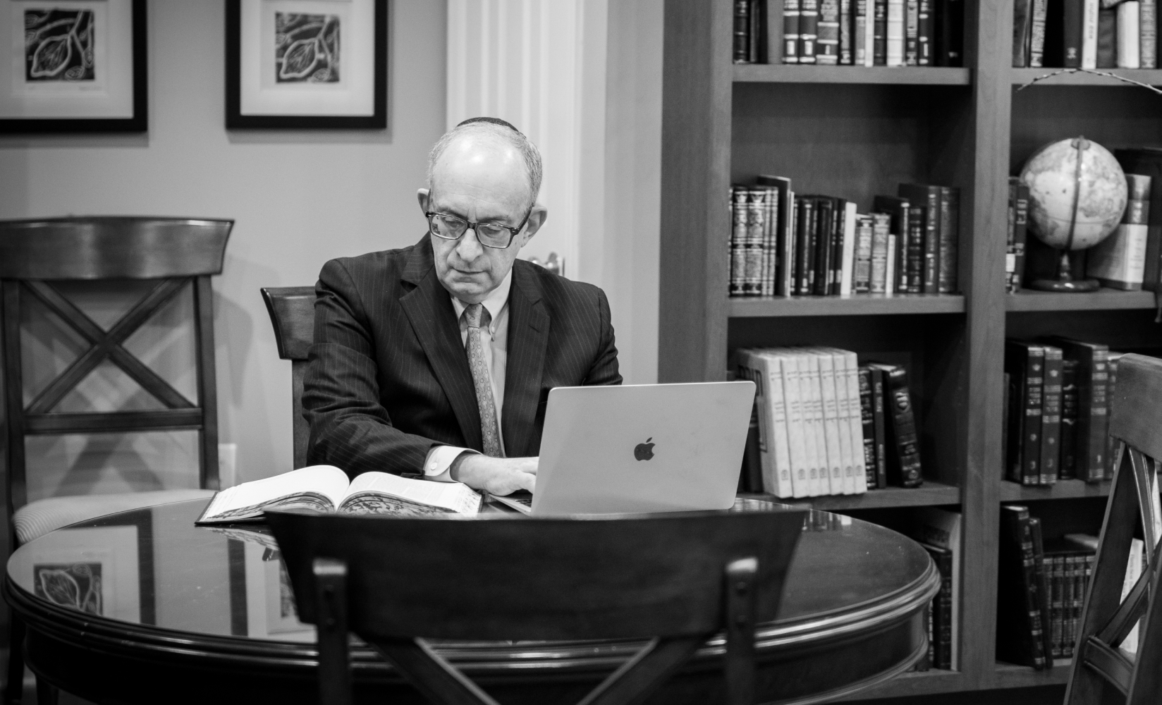 Kadish using his computer in his home office, with large bookshelf in background